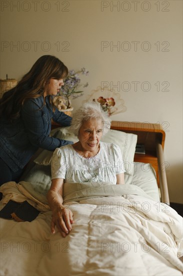 Granddaughter helping grandmother into bed