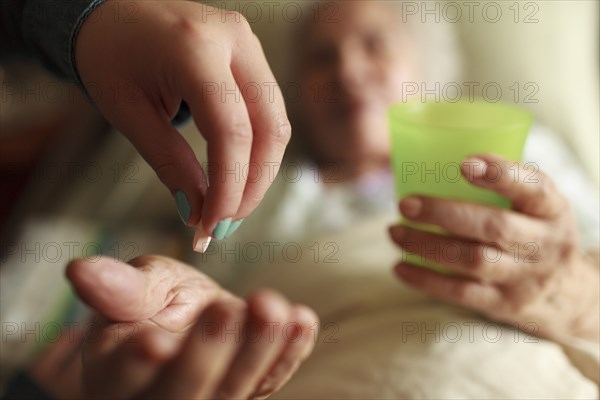 Granddaughter giving grandmother medication in bed