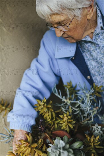 Older mixed race woman caring for potted plants