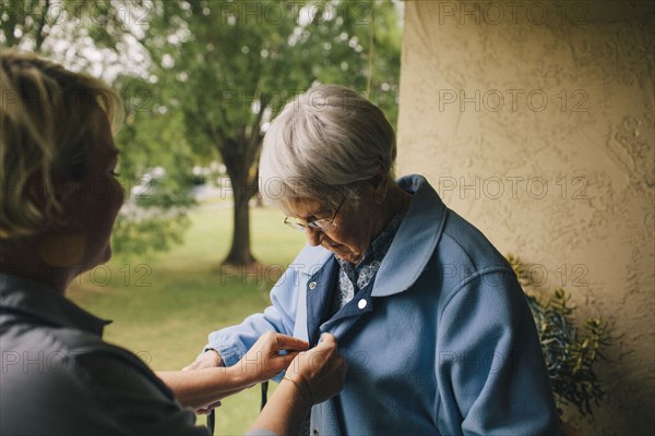 Older woman and granddaughter standing on balcony