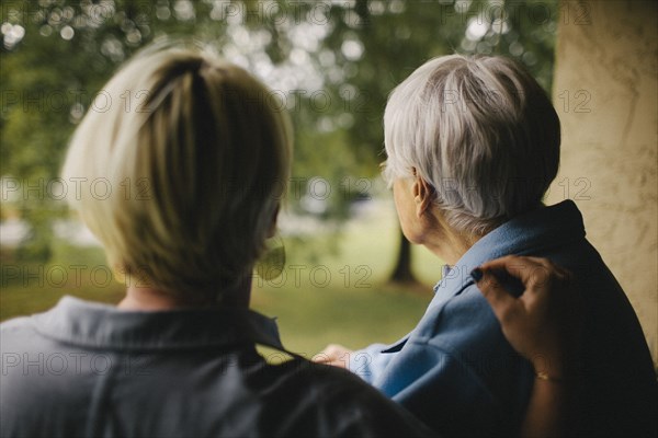 Older woman and granddaughter standing on balcony