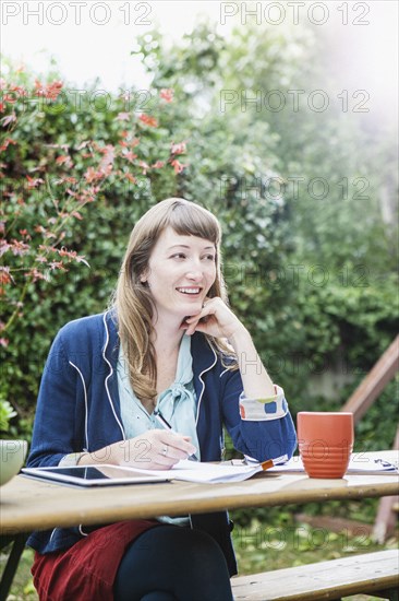 Mixed race businesswoman writing notes in backyard