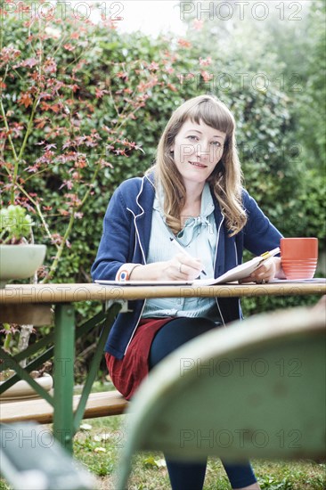 Mixed race businesswoman writing notes in backyard