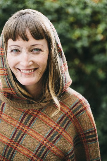 Mixed race woman wearing hood and shawl in backyard