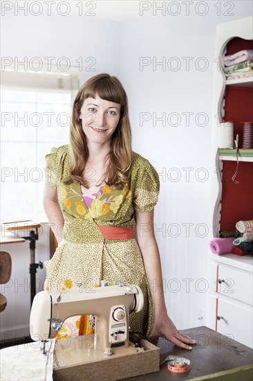 Mixed race dressmaker smiling at sewing table