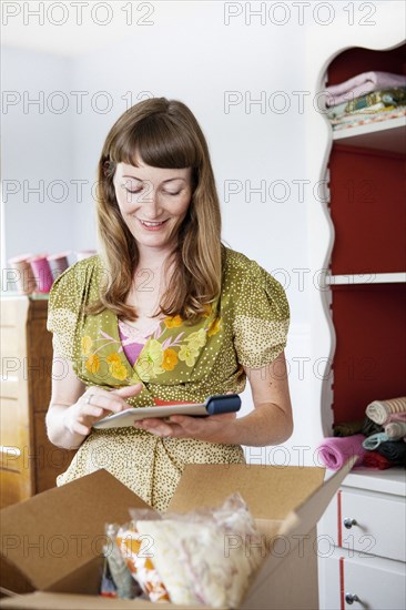 Mixed race dressmaker using digital tablet at sewing table