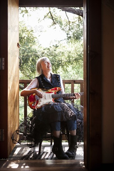 Caucasian woman playing electric guitar on porch