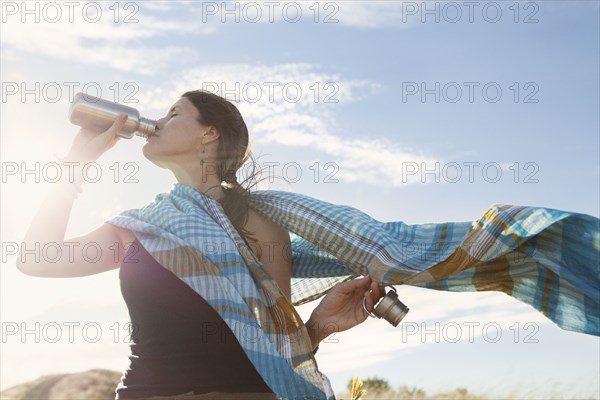 Caucasian woman drinking from bottle in wind