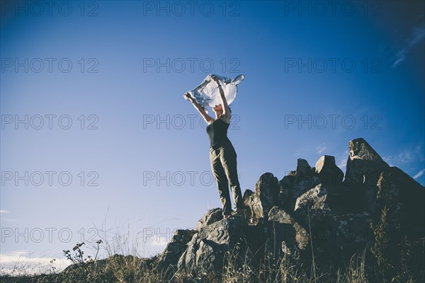 Caucasian woman playing with scarf on remote hilltop