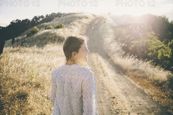 Caucasian woman walking on rural dirt road