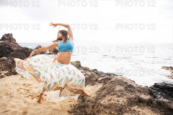 Woman dancing on rocky beach