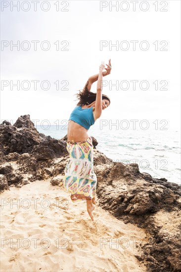 Woman dancing on rocky beach