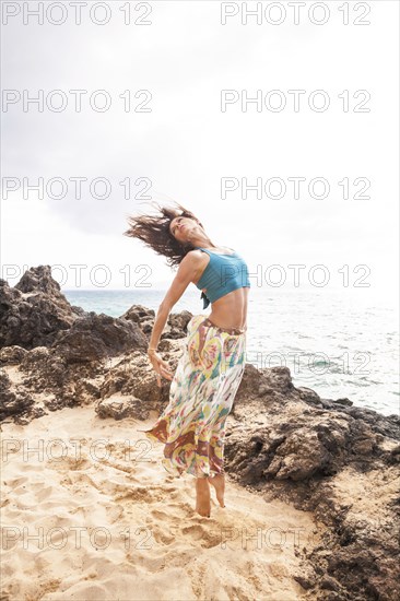 Woman dancing on rocky beach