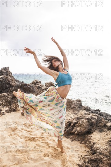 Woman dancing on rocky beach