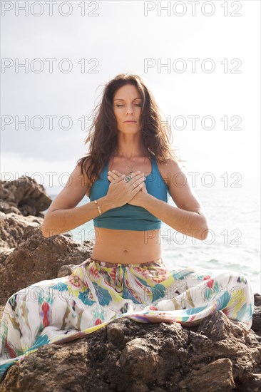 Close up of woman meditating on rocky beach