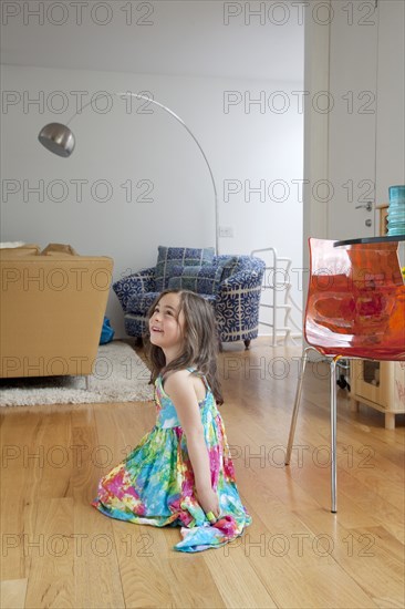 Caucasian girl sitting on living room floor