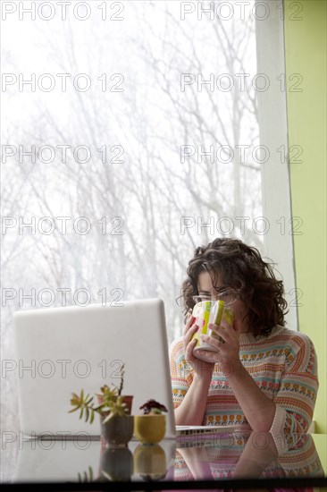 Caucasian businesswoman drinking coffee at desk