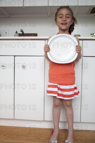 Caucasian girl holding empty plate in kitchen