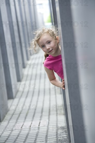 Caucasian girl peeking around corner in hallway