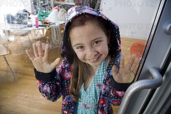 Mixed race girl looking out rainy window