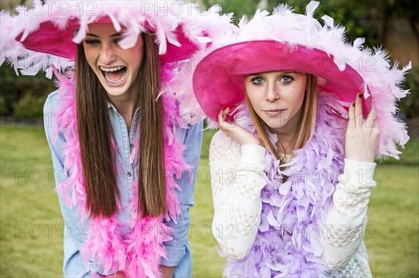 Caucasian teenage girls wearing feather boas and hats