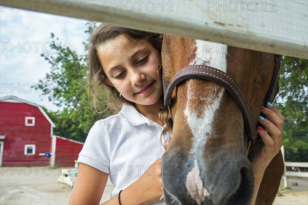 Close up of teenage girl hugging horse on ranch