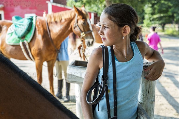 Frowning girl standing at post on ranch