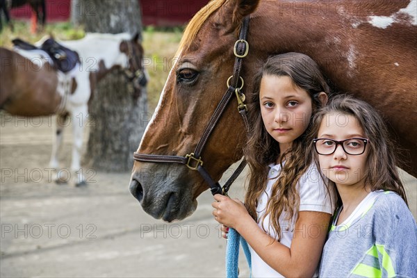 Serious girls leading horse on ranch