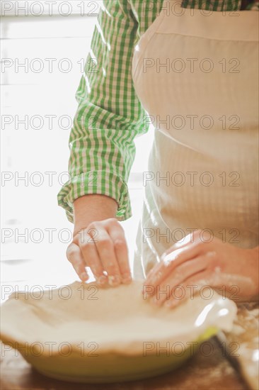 Baker pressing pie dough in dish