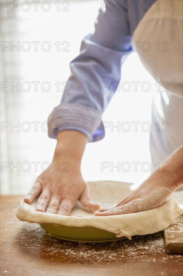 Baker pressing pie dough in dish