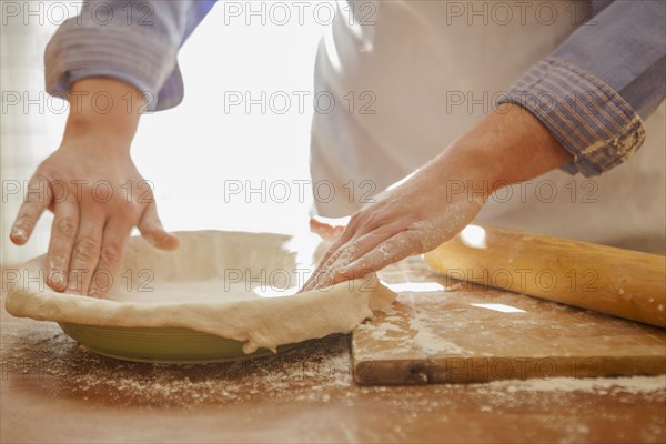 Baker pressing pie dough in dish