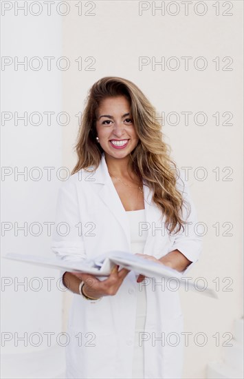 Smiling Hispanic doctor reading folder