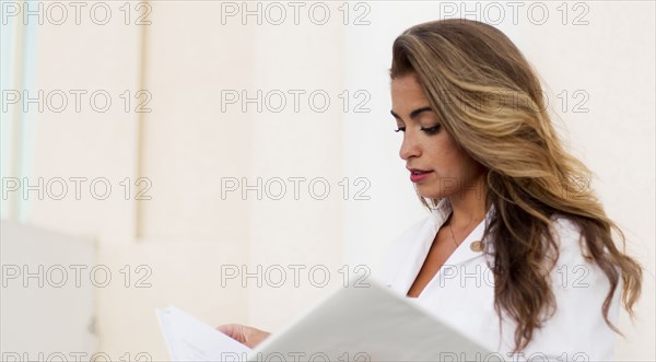 Smiling Hispanic doctor reading folder