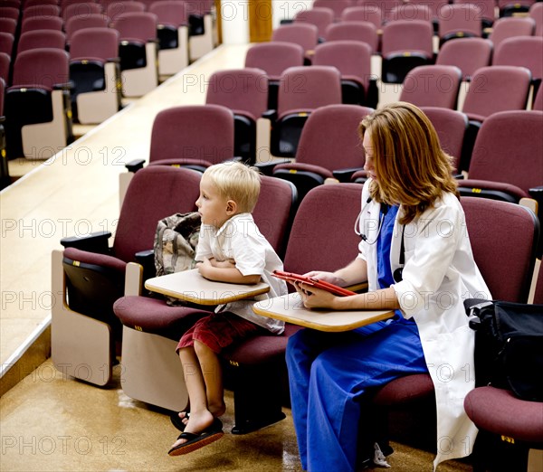 Student doctor and son sitting in college classroom