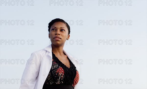 Serious doctor standing under blue sky