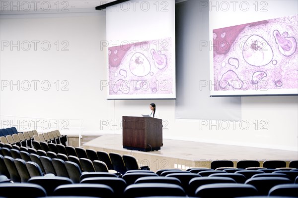 Armenian doctor speaking at podium in empty classroom