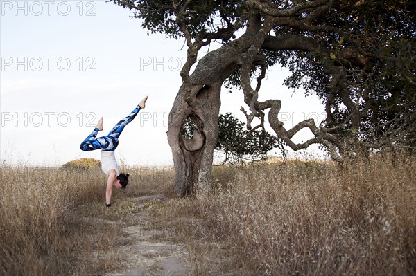 Caucasian woman practicing yoga in field