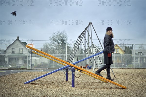 Caucasian woman walking on playground seesaw