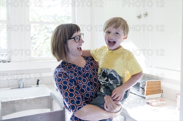 Mother holding son in kitchen