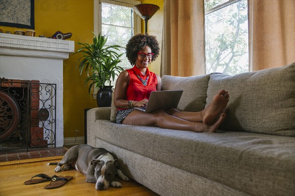 Mixed race woman using laptop on sofa