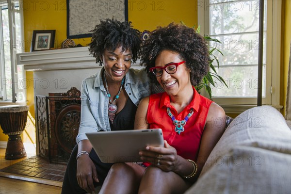 Women using digital tablet on sofa