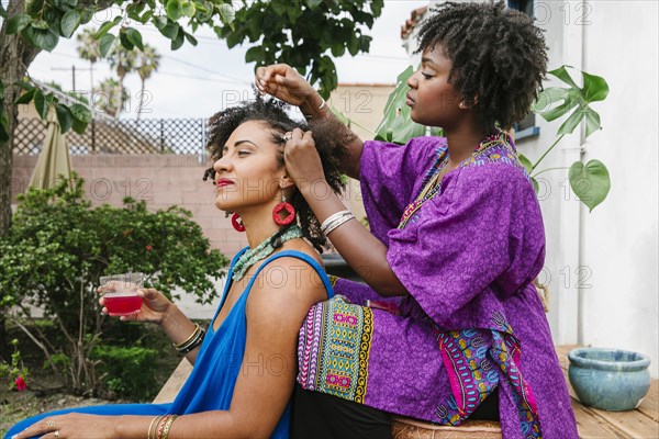 Woman combing hair of friend on front stoop