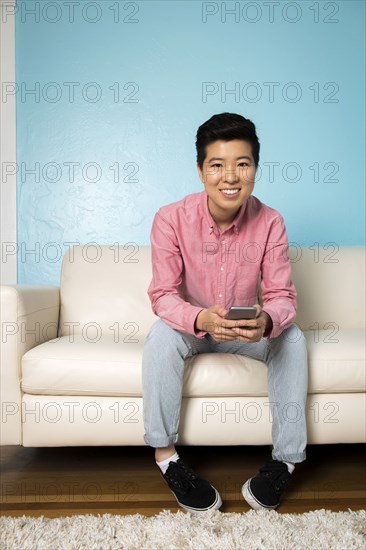 Androgynous woman using cell phone on sofa