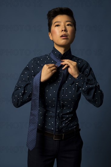 Androgynous woman tying tie