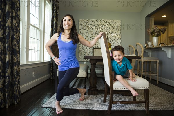 Mother stretching with son in dining room