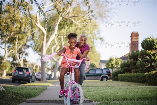 Mother pushing daughter on bicycle