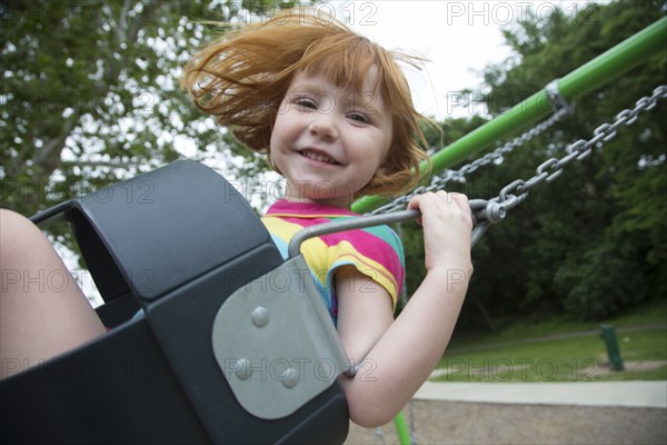 Caucasian girl playing on swing