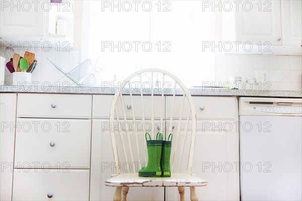 Rain boots of child on chair near kitchen sink