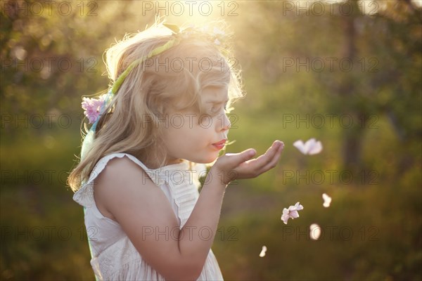 Caucasian girl blowing flower petals outdoors