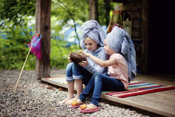 Caucasian sisters with hair towels examining bird nest